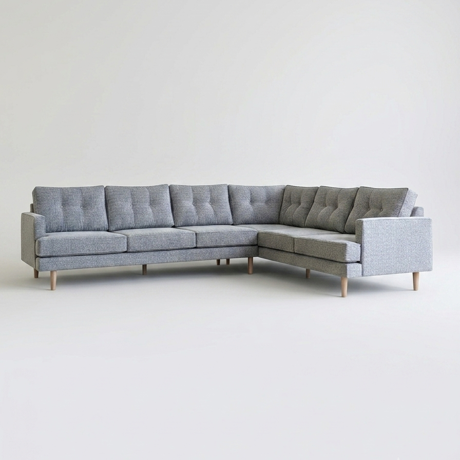 A modern L-shaped sectional sofa upholstered in light gray fabric with tufted back cushions and light wood legs
